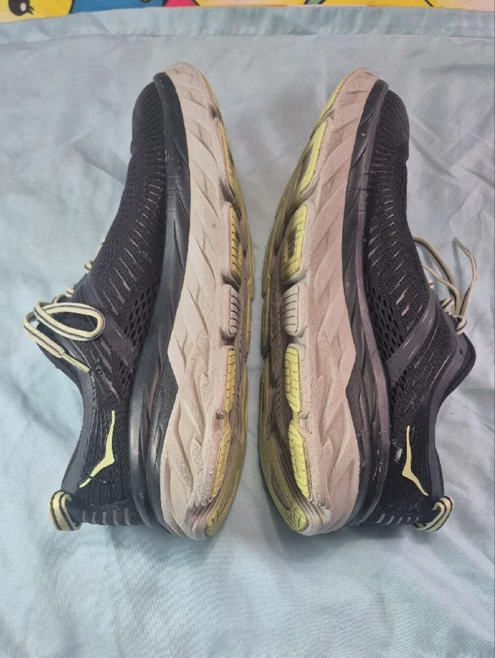 Hoka black running shoes with pale yellow logo